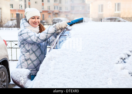 Attraktive Frau Bürsten Schnee von der Windschutzscheibe Stockfoto