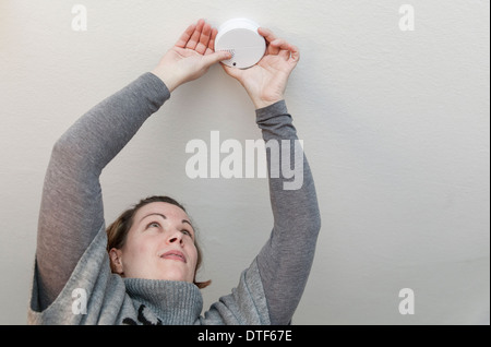 Berlin, Deutschland, sammelt eine Frau einen Rauchmelder an der Decke Stockfoto