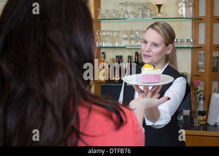 Kellnerin Hände einen Stück Kuchen an Kunden Stockfoto