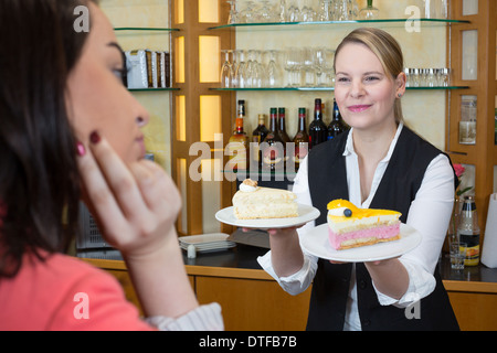 Ladenbesitzer in der Konditorei bietet Kunden ein Stück Kuchen und Kaffee Stockfoto