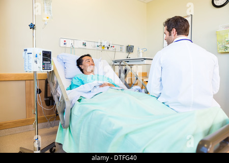 Lächelnd Patienten betrachten Arzt am Krankenbett liegend Stockfoto