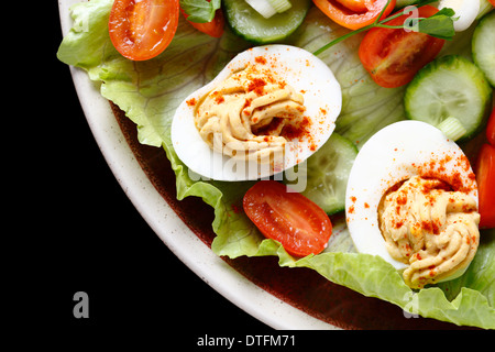 Hausgemachte deviled Eiern serviert auf einem Salat von Miniatur-Tomaten, Salat, Gurken und gehackte Frühlingszwiebeln Frühlingszwiebeln. Stockfoto
