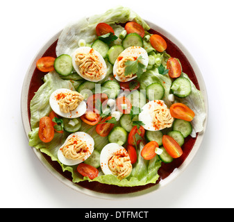 Hausgemachte deviled Eiern serviert auf einem Salat von Miniatur-Tomaten, Salat, Gurken und gehackte Frühlingszwiebeln Frühlingszwiebeln. Stockfoto