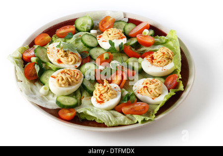 Hausgemachte deviled Eiern serviert auf einem Salat von Miniatur-Tomaten, Salat, Gurken und gehackten grünen Frühlingszwiebeln, Seitenansicht Stockfoto