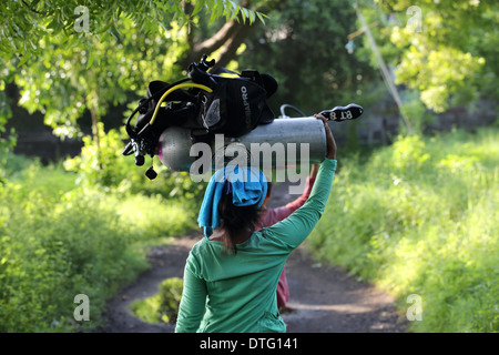 Balinesischen Frauen tragen Tauchflaschen Tauchen zu einem Tauchplatz, Portier-Service bereitgestellt, wenn in Tulamben, Ost Bali Tauchen Stockfoto