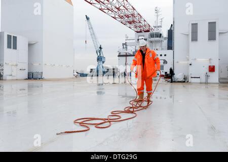 Hamburg, Deutschland. 17. Februar 2014. Ein Besatzungsmitglied Gewölbebaus ein Seil auf dem Deck des Wind Turbine Installation Schiff Aeolus auf der Sietas-Werft in Hamburg, Deutschland, 17. Februar 2014. Aeolus ist das erste Wind Turbine Installation Schiff entworfen und gebaut in Deutschland und wird für den Bau von Windkraftanlagen an der Eneco Luchterduinen Windpark ab Juli 2014 von Van Oord verwendet werden. Foto: MARKUS SCHOLZ/DPA/Alamy Live-Nachrichten Stockfoto
