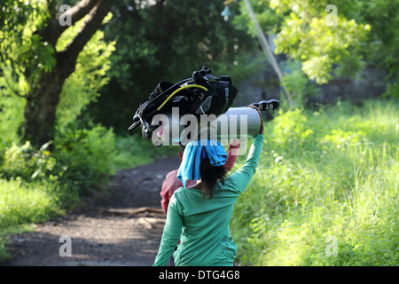 Balinesischen Frauen tragen Tauchflaschen Tauchen zu einem Tauchplatz, Portier-Service bereitgestellt, wenn in Tulamben, Ost Bali Tauchen Stockfoto