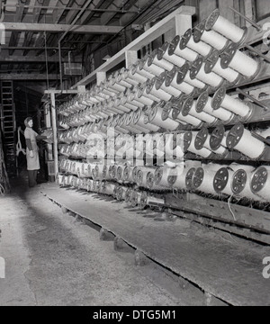 1950er und eine historische Bild zeigt eine industrielle Textilfabrik und eine große Bank von Garn Spulen. Stockfoto