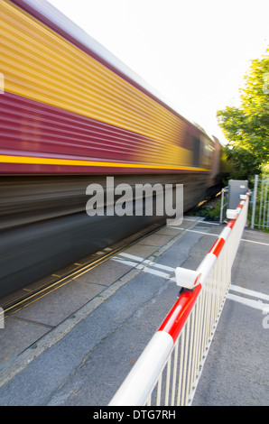 Ein Bild von einem Güterzug mit Geschwindigkeit bei einem Bahnübergang genommen. Stockfoto