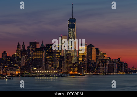 Die untergehende Sonne verschönert die unteren Skyline von New York City. Umgeben von anderen NYC Wolkenkratzer ist der New Freedom Tower Stockfoto