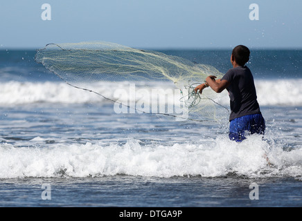 Junge in die Brandung am Strand von Mechapa, Nicaragua Pazifikküste Netz auswarf Stockfoto