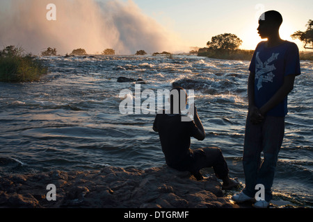 Touristen besuchen die Victoriafälle. Diese gehören zu den spektakulärsten Wasserfälle der Welt. Der Sambesi. Stockfoto