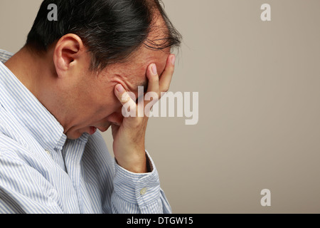 Deprimiert asiatischer Mann allein hielt seinen Kopf Stockfoto