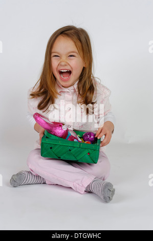 Lachende Mädchen hält ein Osternest mit Schokolade Osterhasen Stockfoto