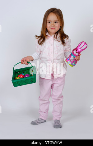 Mädchen hält ein Osternest und eine Schokolade Osterhasen Stockfoto