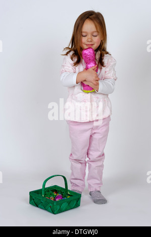 Eine Mädchen mit einem Osternest ist eine Schokolade Osterhasen umfassend. Stockfoto