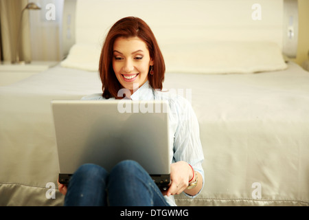 Glückliche Frau mit Laptop zu Hause sitzen Stockfoto