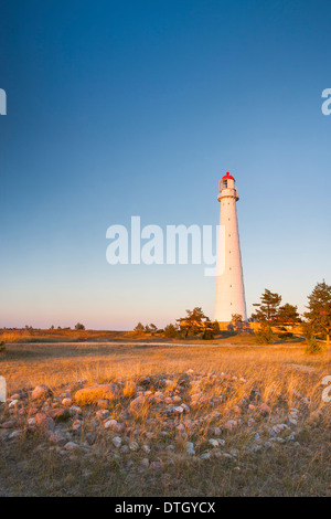 Hohe schlanke weiße Leuchtturm oder Leuchtturm, bekannt als Tahkuna bei Sonnenuntergang in Hiiumaa, Estland und Steinlabyrinth oder Labyrinth im Vordergrund. Stockfoto