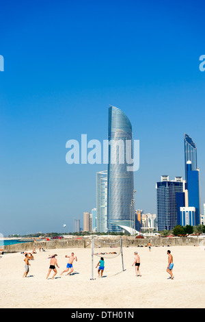 Volleyballspiel am Strand von Corniche mit Skyline in Abu Dhabi Vereinigte Arabische Emirate Stockfoto