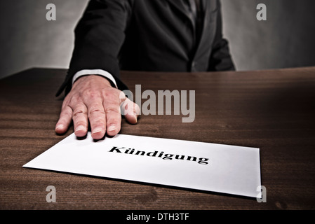 Mann, der einen Brief mit der Kündigung des Arbeitsvertrags auf dem Schreibtisch. Stockfoto