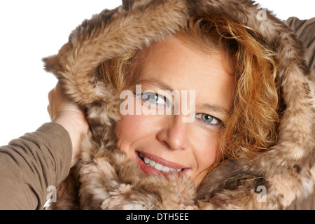 Studioaufnahme einer lächelnden blonden Frau mit blauen Augen tragen eine Fell Kapuze über einen weißen Hintergrund. Stockfoto