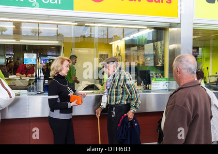 Ein paar an einem Auto mieten Schalter im Ankunftsbereich auf Teneriffa Süd Flughafen, Kanarische Inseln, Spanien. Stockfoto