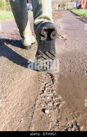 Fußgänger im grünen Wellington boots zeigen Sohle von Boot und Impressum Links im Schlamm Stockfoto