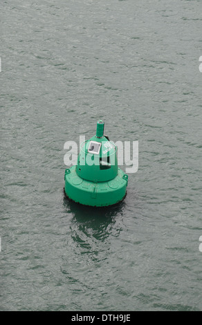 Eine grüne Boje Fahrwassermarkierung (IALA-A Steuerbord Hand Marker) schwebend in Milford Haven, Pembrokeshire, Wales. Stockfoto