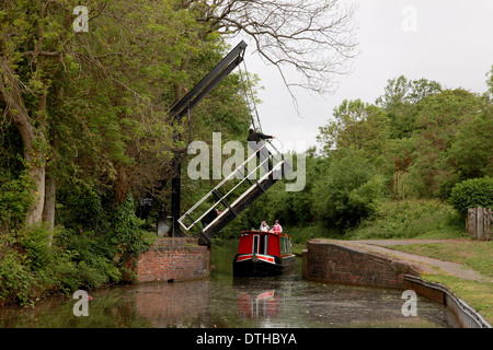 Ein Mann stand auf der erhöhten Hubbrücke in Hockley Heath auf der Stratford on Avon Kanal mit einem Narrowboat unter Stockfoto