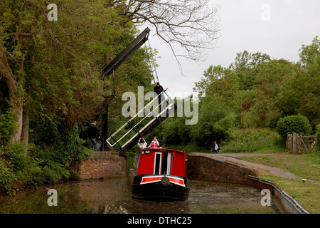 Ein Mann stand auf der erhöhten Hubbrücke in Hockley Heath auf der Stratford on Avon Kanal mit einem Narrowboat unter Stockfoto