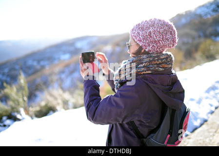 Junge Frau nimmt Fotos mit Handy im Winter Umgebung Stockfoto