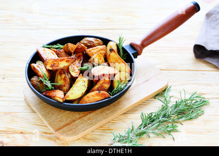 Kartoffelspalten mit Rosmarin in einer Pfanne, Essen Nahaufnahme Stockfoto