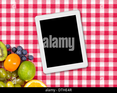 Tablet und Früchte auf Tischdecke Textil Stockfoto