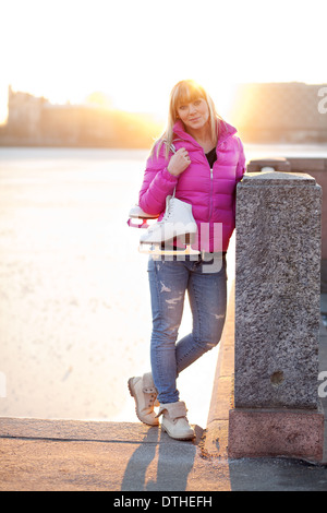 Blonde Frau mit Schlittschuhen Stockfoto