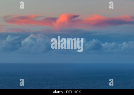 Cumulus-Wolken und rote Cirruswolken über dem Meereshorizont bei Sonnenuntergang. Blick vom Mallorca, Balearen, Spanien Stockfoto