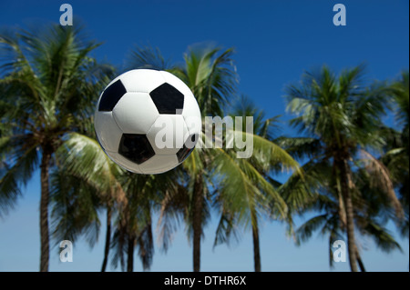 Fußball-Fußball-Ball fliegen in brasilianischen tropischen Strand-Szene mit Palmen und blauer Himmel Stockfoto