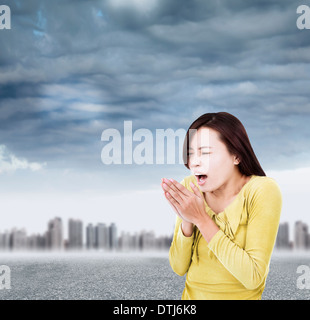 junge Frau für warme Hände Sprengung mit schwarzen Wolken im Aussenbereich Stockfoto