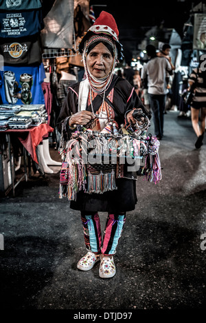 Wanderarbeiter. Ältere ethnische Birmanerin des Akha-Hügels-Stammes, die auf einem thailändischen Nachtmarkt Touristengeschenke verkauft. Thailand S. E. Asien Stockfoto