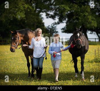 Eine Frau und ein Junge, der zu Fuß in ein Feld mit zwei Pferden England Stockfoto