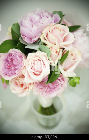 Ein Brautstrauß Pastell gefärbt rosa Rosen und blasses Lavendel Pfingstrosen mit kleinen grünen Blättern England Stockfoto