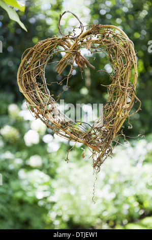 Die Form eines Herzens aus geflochtenen Zweigen hängen von einem Baum einfache Dekorationen England gemacht Stockfoto
