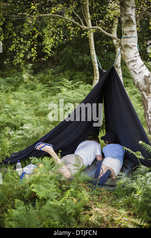 Zwei jungen im New Forest camping liegen unter einer Leinwand Unterschlupf Hampshire England Stockfoto