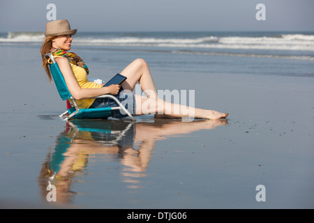 Eine Frau in einem Sonnenhut und Schal am Strand auf der New Jersey Shore-Sitzung mit einem digital-Tablette Ocean City New Jersey USA Stockfoto
