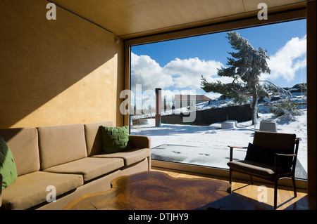 Wohnzimmer mit großem Fenster mit Blick auf eine verschneite Landschaft Stockfoto