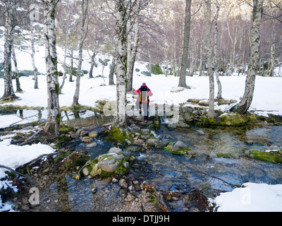 Wanderer, die über einen Fluss im Winter Stockfoto