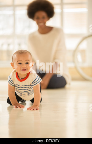 Mutter beobachten Baby Boy kriechen am Boden Stockfoto