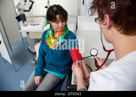 Arztpraxis. Ein Assistent prüft den Blutdruck einer Patientin. Stockfoto
