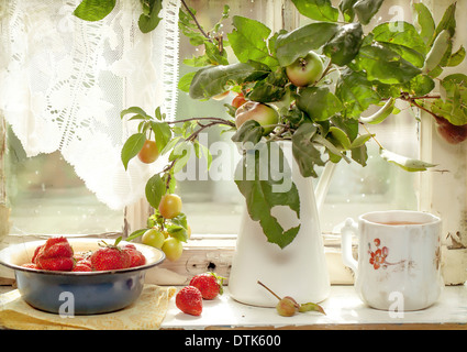Äpfel und frische Erdbeeren auf der alten Fensterbank Stockfoto