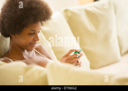 Frau mit Handy auf sofa Stockfoto