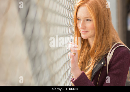 Frau spähte durch Maschendrahtzaun Stockfoto